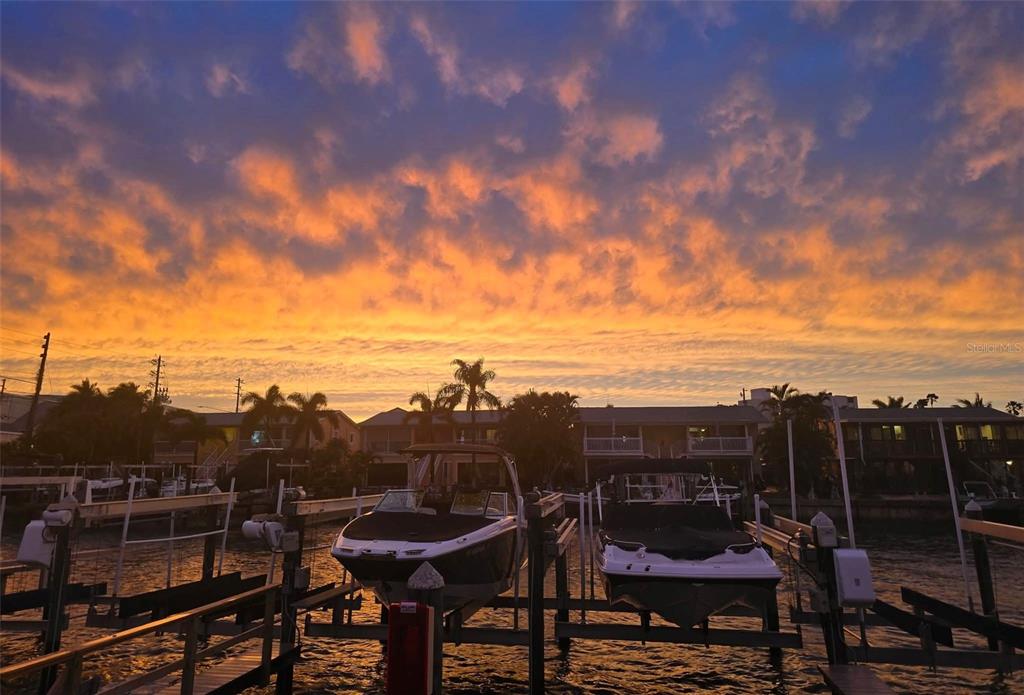 A sunset view of two boats docked at a marina in front of waterfront homes — 2600 N PAULA DRIVE UNIT 12D, DUNEDIN, FL