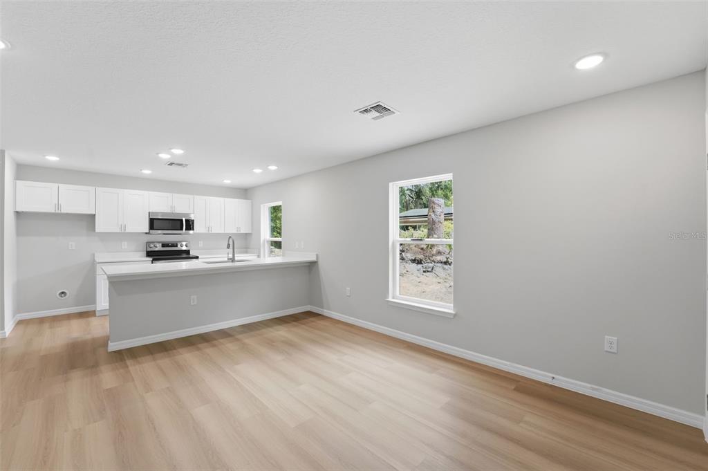 A room with light gray walls, wood-look flooring, a white exterior door, and an attached bathroom — 522 PALMETTO STREET, EUSTIS, FL
