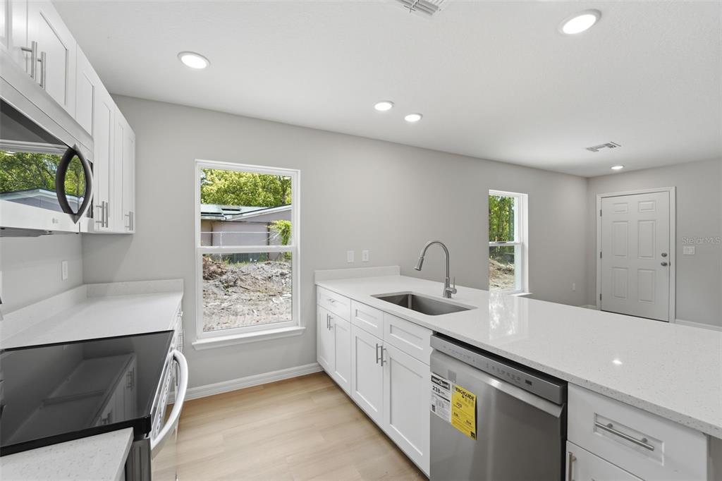 An empty room with light-colored walls, wood-look flooring, and three white interior doors — 522 PALMETTO STREET, EUSTIS, FL