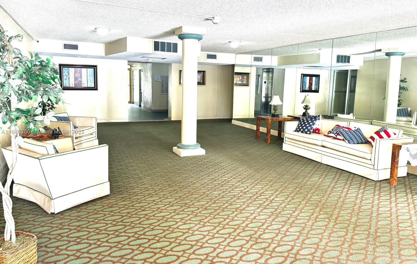 A carpeted lobby features white sofas, a central pillar, and mirrored walls — 6911 SW 147th Ave # 3C, Miami FL 33193, MIAMI, FL