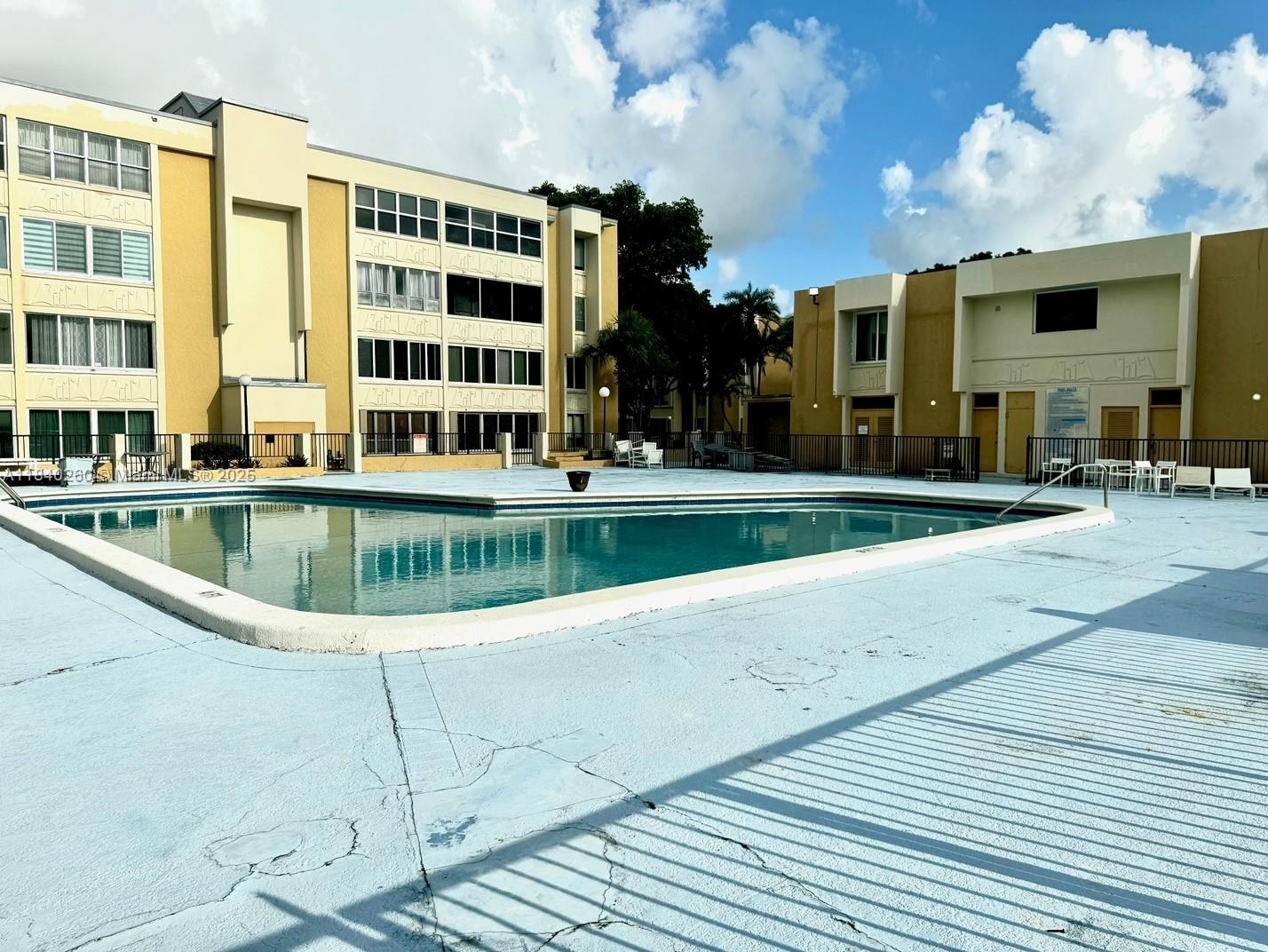 An outdoor swimming pool is surrounded by a light blue deck and multi-story apartment buildings — 6911 SW 147th Ave # 3C, Miami FL 33193, MIAMI, FL