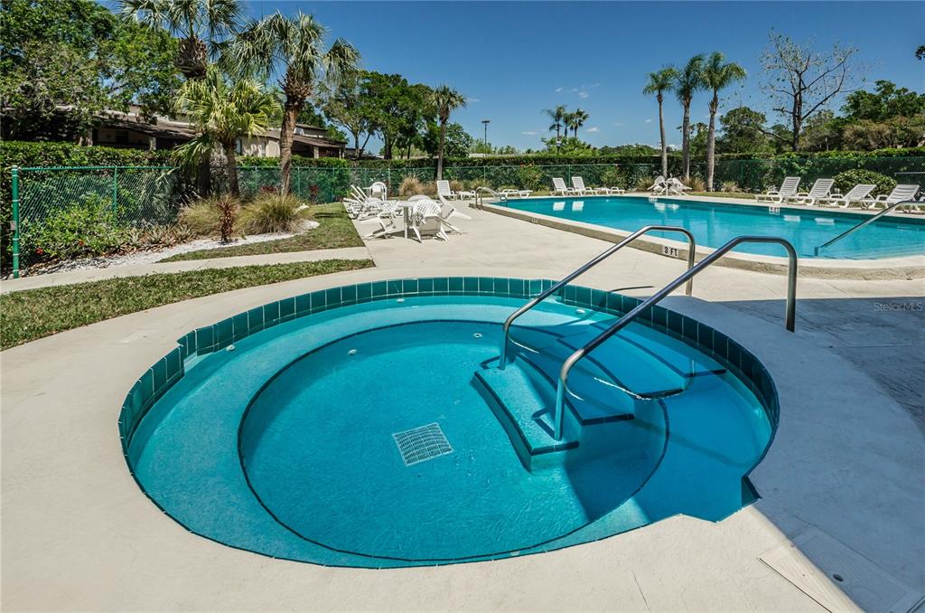 A living room with tile floors, a ceiling fan, and sliding glass doors overlooking a pond — 3505 TARPON WOODS BOULEVARD UNIT O-403, PALM HARBOR, FL