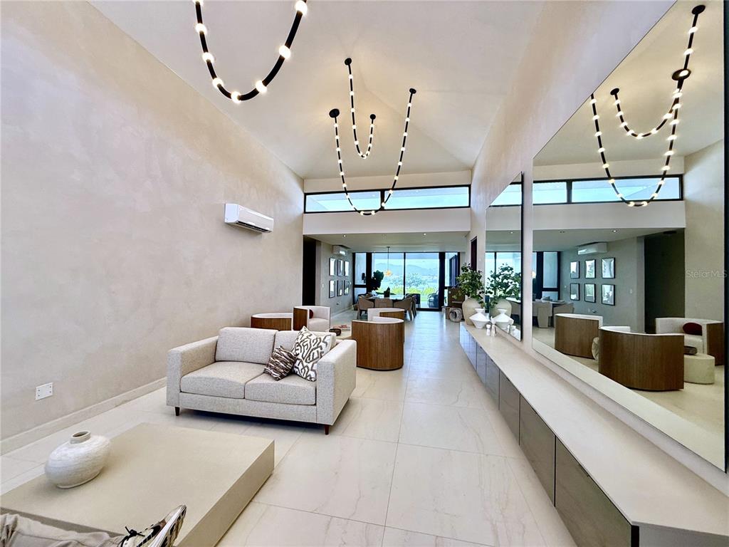 A modern living room features high vaulted ceilings, unique pendant lighting, and a large mirror — 9 LOS LAGOS, HUMACAO, PR