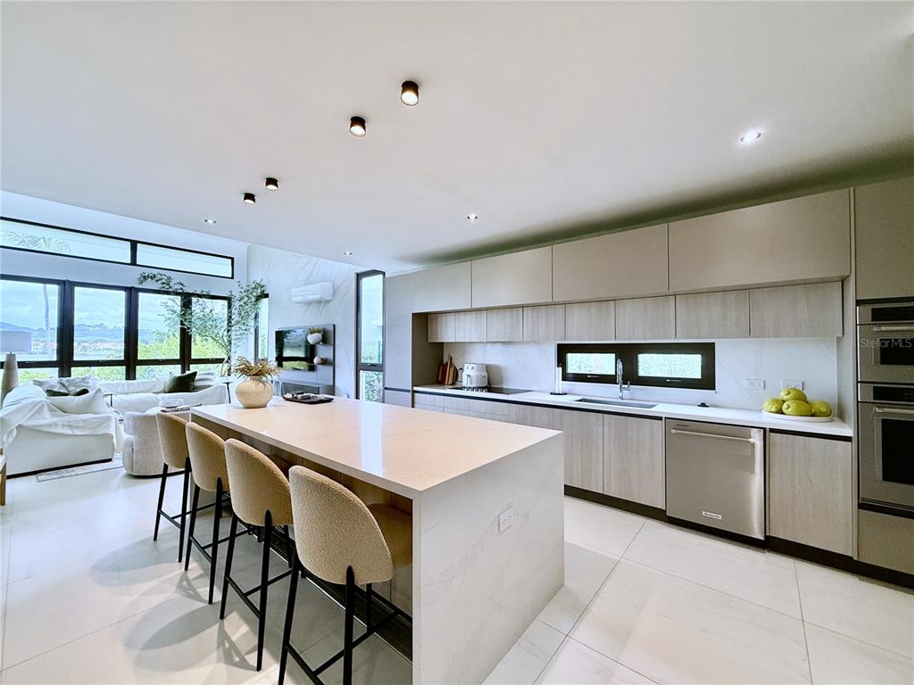 A modern kitchen features a large white island, light wood cabinetry, and stainless steel appliances — 9 LOS LAGOS, HUMACAO, PR
