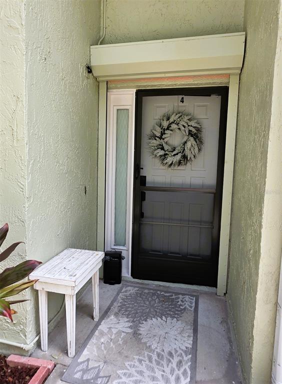 An exterior entryway features a white door with a wreath, a storm door, and a bench — 1761 CUPECOY CIRCLE UNIT N4, LUTZ, FL