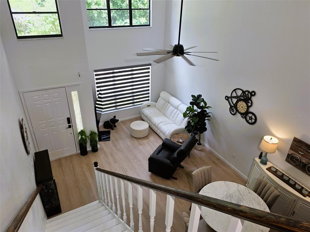 A high-angle view of a living room with white walls, light wood flooring, and stairs — 1761 CUPECOY CIRCLE UNIT N4, LUTZ, FL