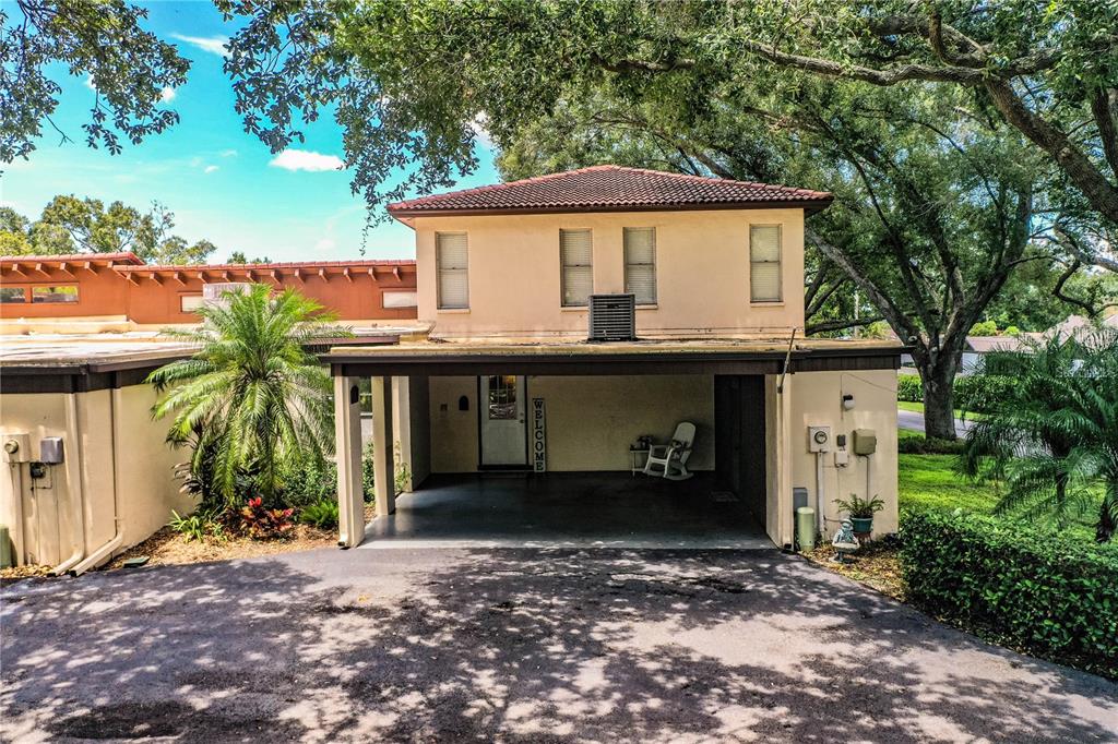 A two-story house with a carport, tan stucco exterior, and a tiled roof — 11 LOMA VERDE UNIT 11, LAKELAND, FL