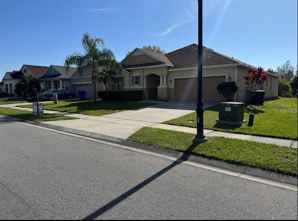 A tan single-story house with a two-car garage and a concrete driveway — 3448 GOLDENEYE LANE, ST CLOUD, FL