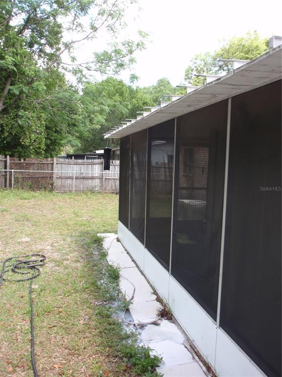 A screened-in porch exterior with a white metal roof and a fenced backyard — 10406 N 26TH STREET, TAMPA, FL