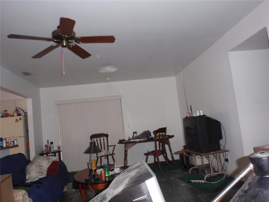 A living room with a ceiling fan, a dining table, and a television on a stand — 10406 N 26TH STREET, TAMPA, FL