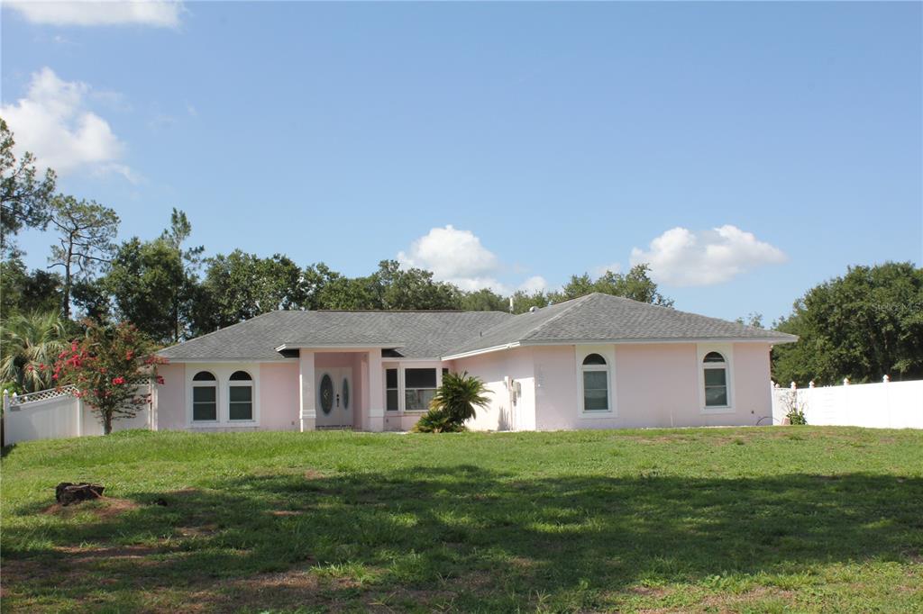 A single-story pink house with a gray roof sits on a grassy lot — 122 QUAILWOOD DRIVE, WINTER HAVEN, FL