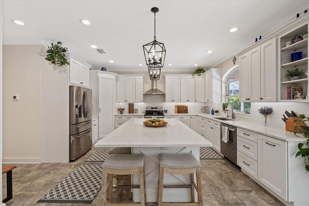 A bright kitchen features white cabinetry, a large central island, and stainless steel appliances — 4151 LA SALLE DRIVE, PALM HARBOR, FL
