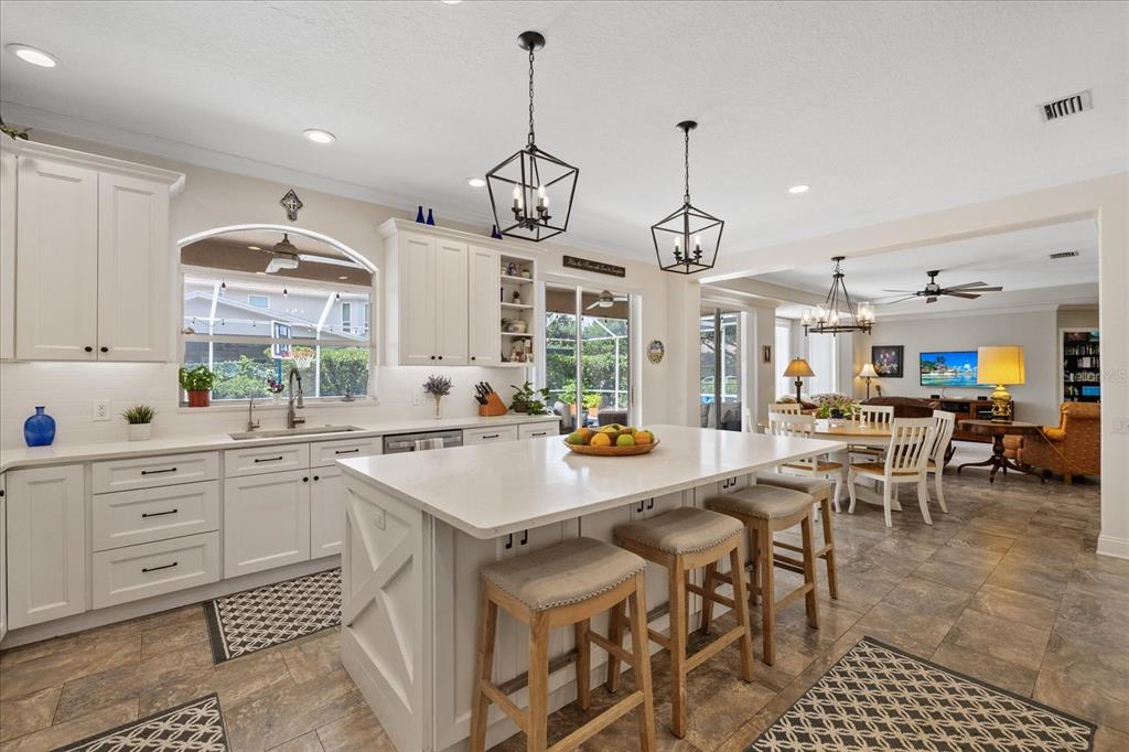 A bright kitchen features white cabinetry, a large central island with seating, and tile flooring — 4151 LA SALLE DRIVE, PALM HARBOR, FL