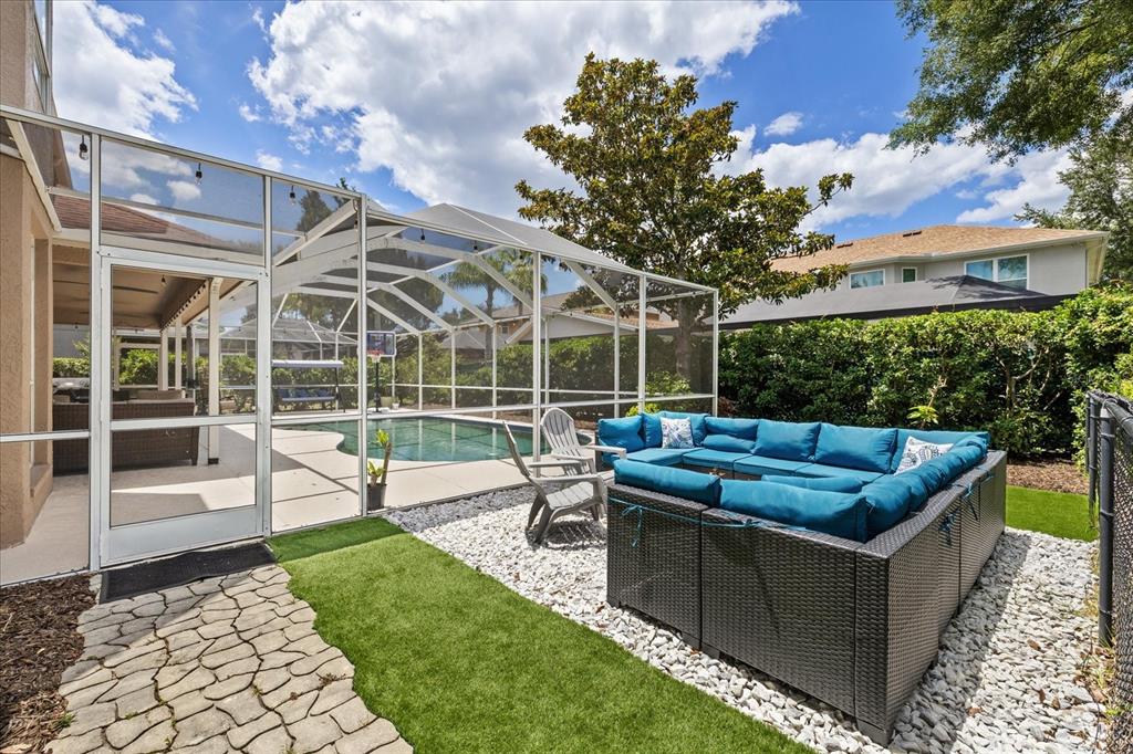 A backyard features a screened-in swimming pool, a blue sectional sofa, and a stone walkway — 4151 LA SALLE DRIVE, PALM HARBOR, FL