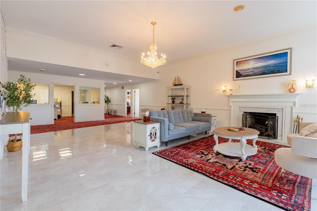 A spacious living room features a fireplace, chandelier, gray sofa, and red patterned area rug — 3530 49TH STREET N, ST PETERSBURG, FL
