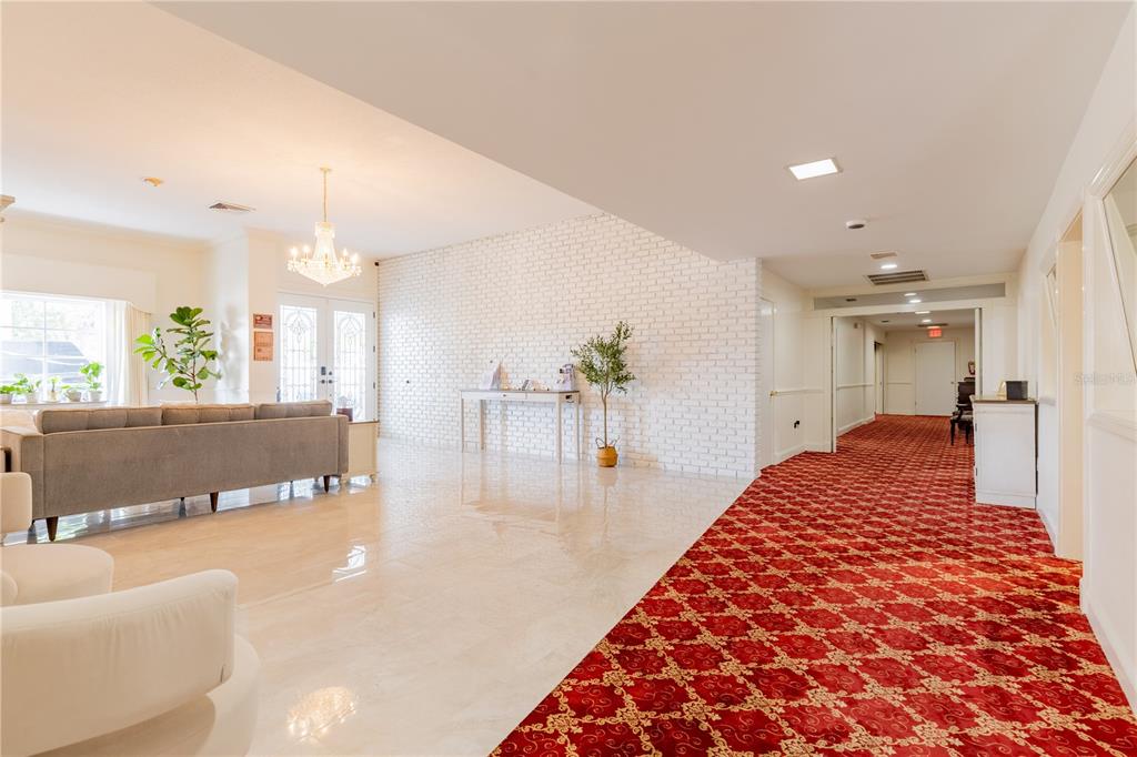 A bright lobby features a white brick wall, polished floors, and a red patterned carpet — 3530 49TH STREET N, ST PETERSBURG, FL