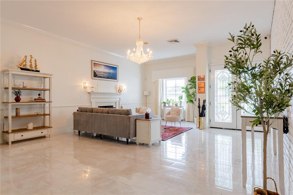 A bright living room features a crystal chandelier, a gray sofa, and white tile flooring — 3530 49TH STREET N, ST PETERSBURG, FL