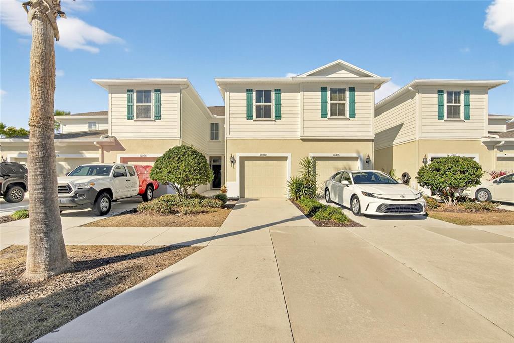 A multi-unit residential building with beige siding, green shutters, and concrete driveways — 10808 VERAWOOD DRIVE, RIVERVIEW, FL