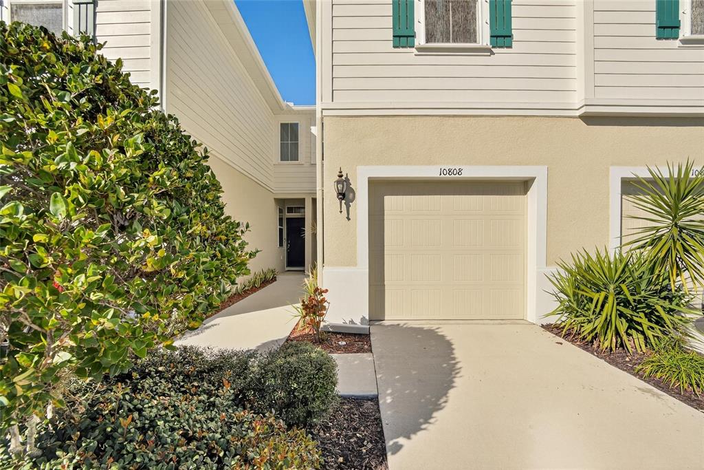 A beige two-story house features a single-car garage and a walkway leading to the entrance — 10808 VERAWOOD DRIVE, RIVERVIEW, FL