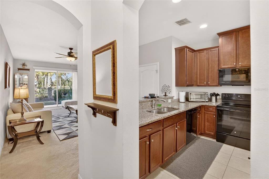 A view from a hallway into a kitchen with wood cabinets and an adjacent living area — 10808 VERAWOOD DRIVE, RIVERVIEW, FL