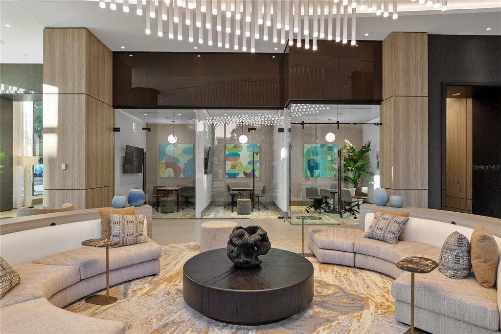 A modern lobby features a curved sofa, a central coffee table, and glass-enclosed meeting rooms — 275 1ST AVENUE S UNIT 4002, ST PETERSBURG, FL