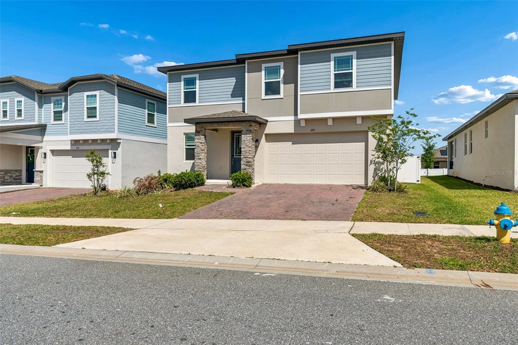 A two-story suburban house with a stone-accented entryway, a two-car garage, and blue siding — 2310 RAVEN RIDGE ROAD, MINNEOLA, FL