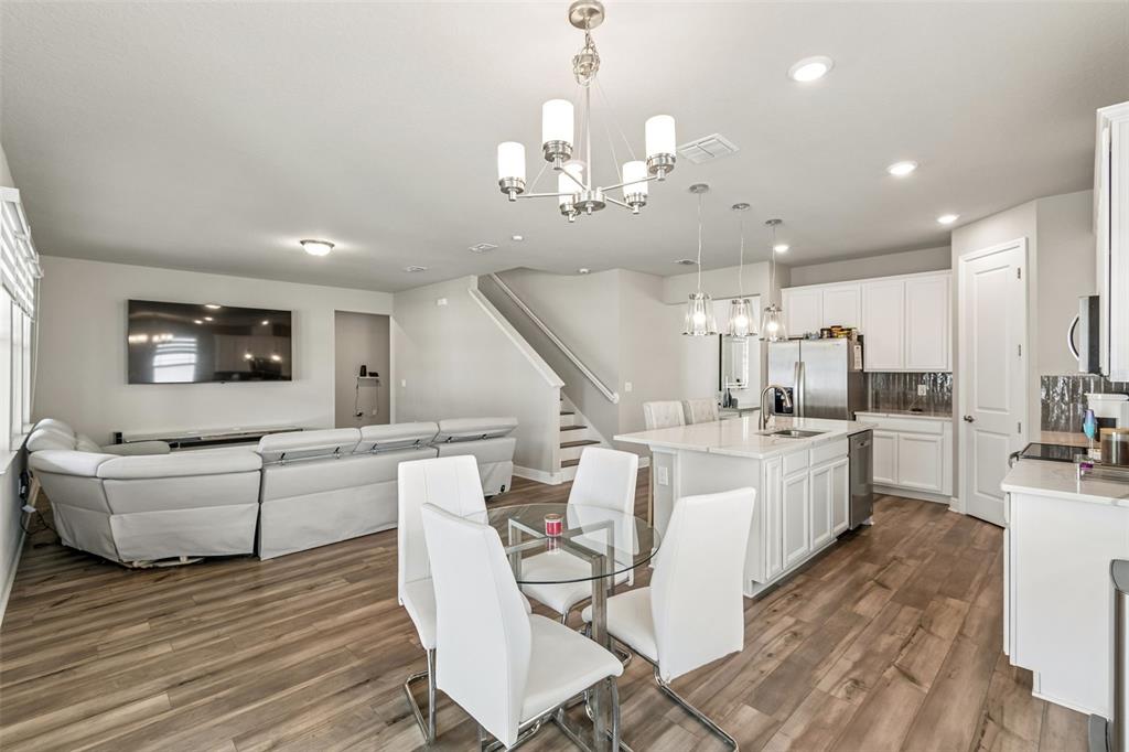 An open-concept living room and kitchen featuring white cabinetry, a central island, and wood flooring — 2310 RAVEN RIDGE ROAD, MINNEOLA, FL