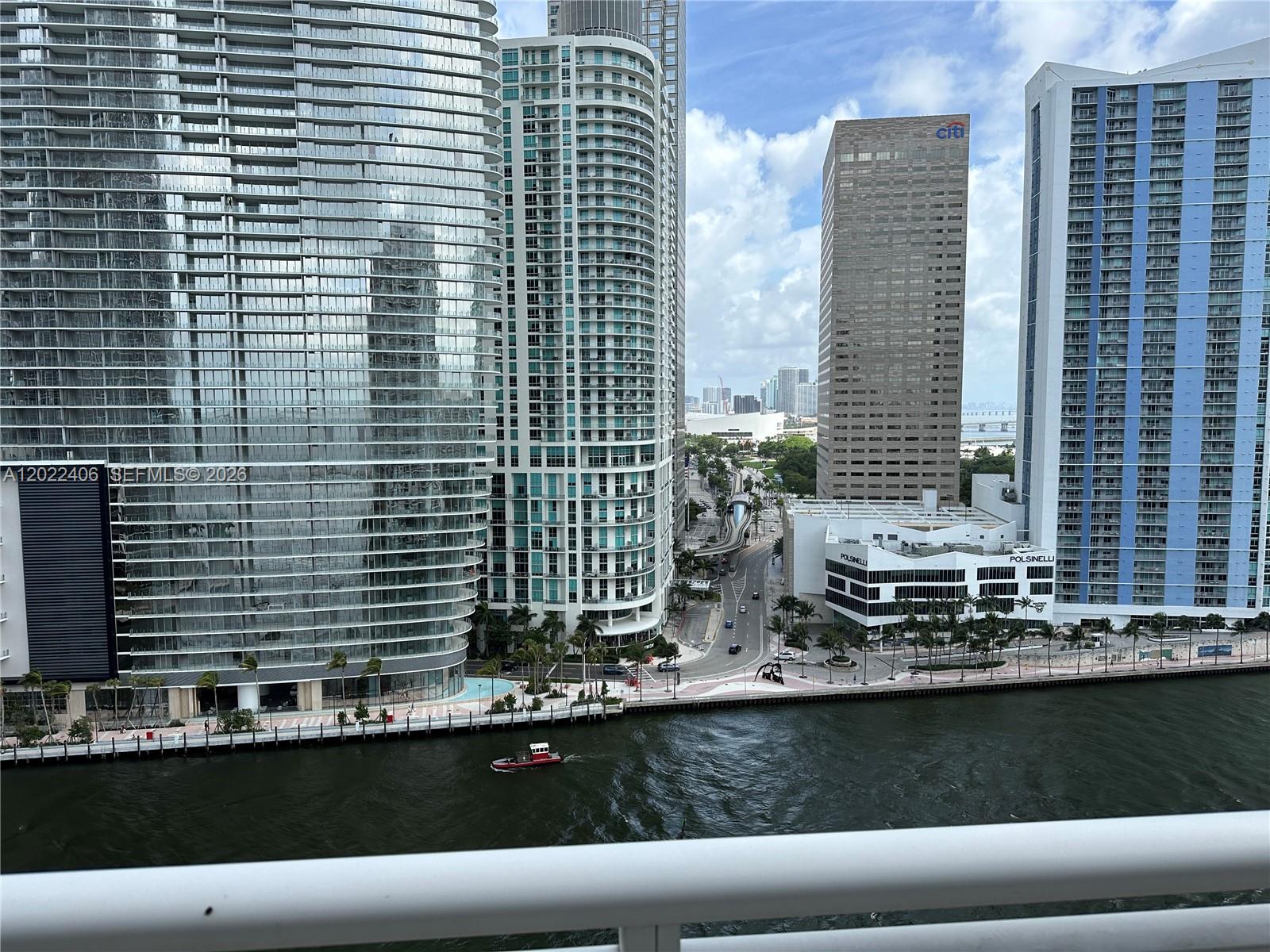 An elevated view of a Miami riverfront with modern skyscrapers and a small boat — 901 Brickell Key Blvd # 2005, Miami FL 33131, MIAMI, FL