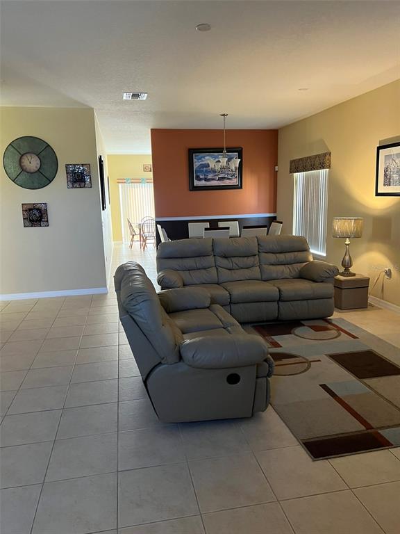 A living room features a gray leather sofa and loveseat on a patterned area rug — 948 HACIENDA CIRCLE, KISSIMMEE, FL