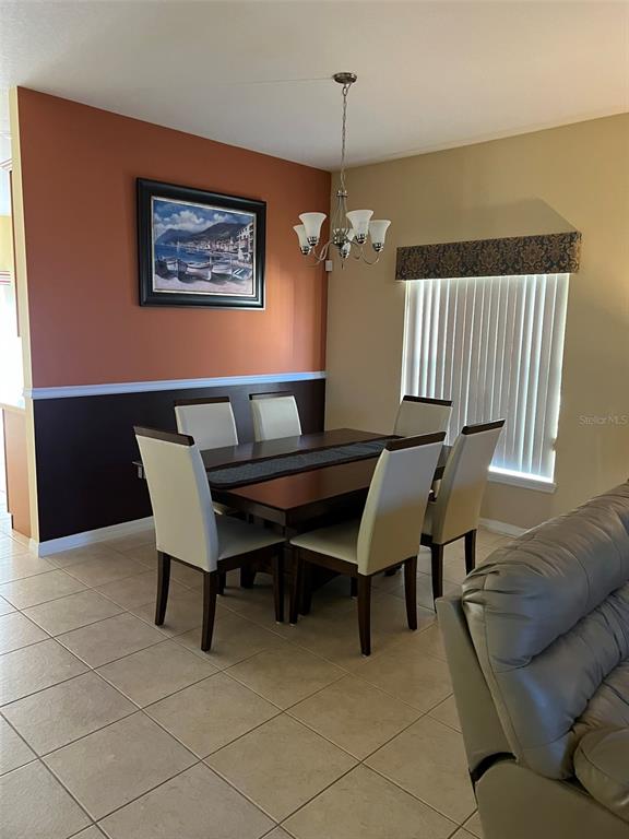 A dining room features a dark wood table, six chairs, and two-toned wall paint — 948 HACIENDA CIRCLE, KISSIMMEE, FL