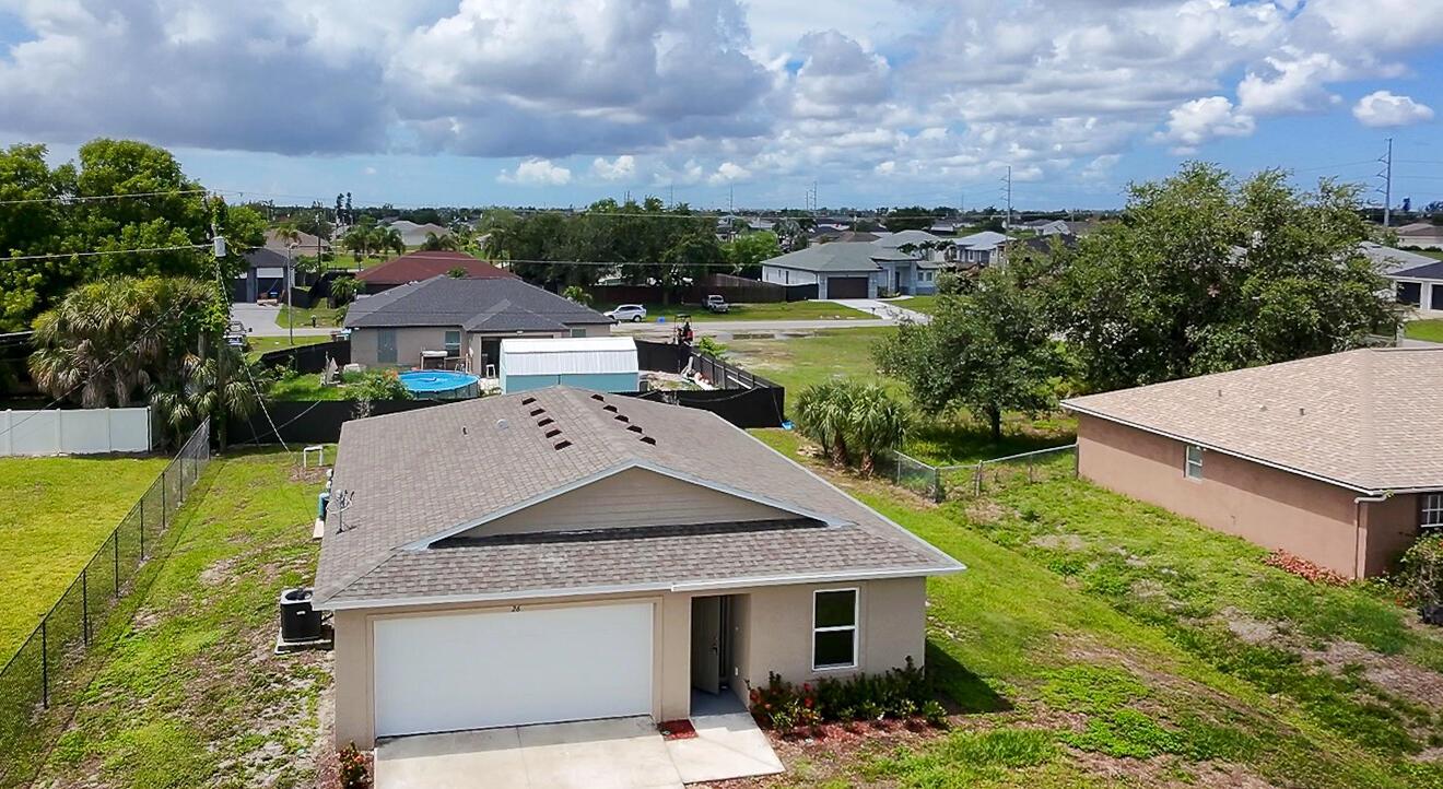 An aerial view of a single-story suburban house with a tan exterior and gray roof — 26 NE 12th Terrace, Cape Coral FL 33909, CAPE CORAL, FL
