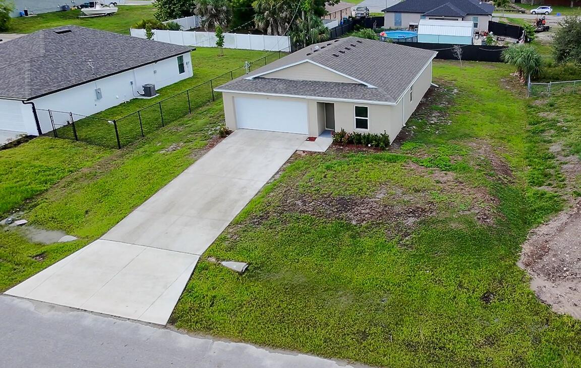 An aerial view of a single-story suburban house with a concrete driveway and grassy yard — 26 NE 12th Terrace, Cape Coral FL 33909, CAPE CORAL, FL