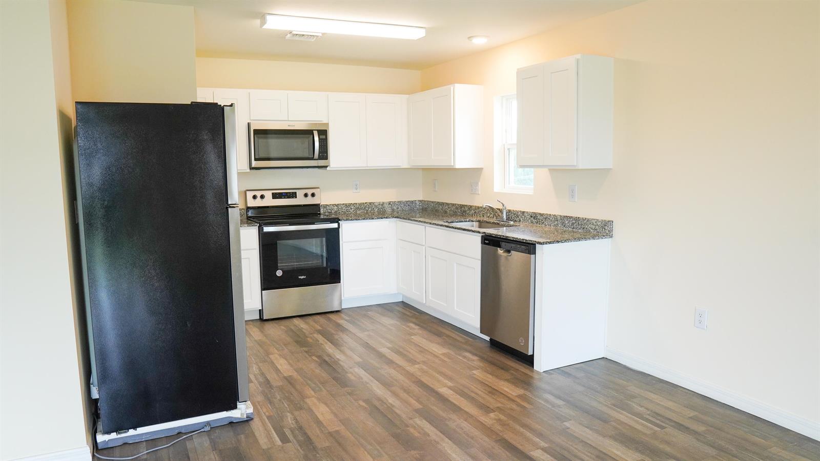 A kitchen features white cabinets, granite countertops, stainless steel appliances, and wood-look flooring — 26 NE 12th Terrace, Cape Coral FL 33909, CAPE CORAL, FL