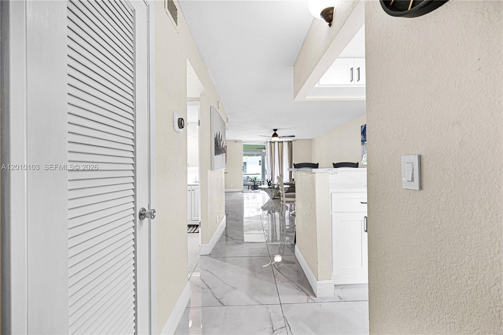A kitchen features white cabinets, stainless steel appliances, and white marble-patterned countertops — 400 SE 10th St # 105, Deerfield Beach FL 33441, DEERFIELD BEACH, FL