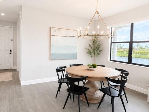 A dining room features a round wooden table, black chairs, and a large metal chandelier — 2915 BLAZING STAR DRIVE, MELBOURNE, FL