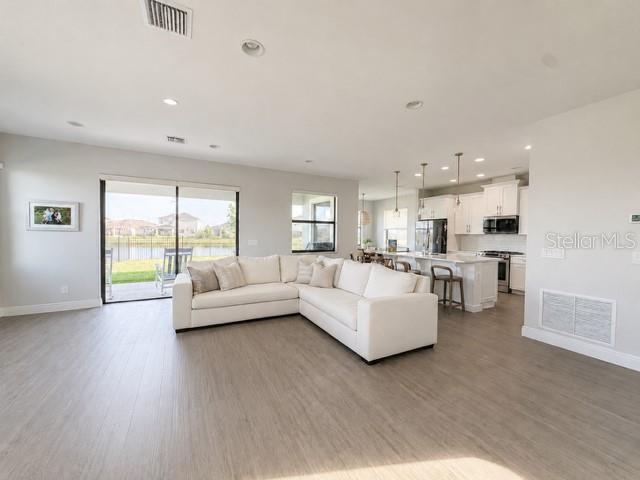 A bright open-concept living room features a large white sectional sofa and a modern kitchen — 2915 BLAZING STAR DRIVE, MELBOURNE, FL