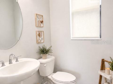 A bathroom features a pedestal sink, a toilet, and two framed wall art pieces — 2915 BLAZING STAR DRIVE, MELBOURNE, FL