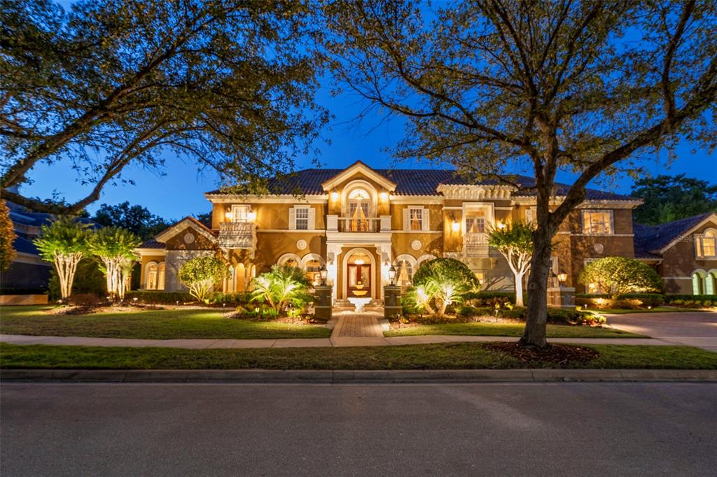 A large, two-story Mediterranean-style house with a tiled roof is illuminated at dusk — 3540 LEGACY HILLS COURT, LONGWOOD, FL