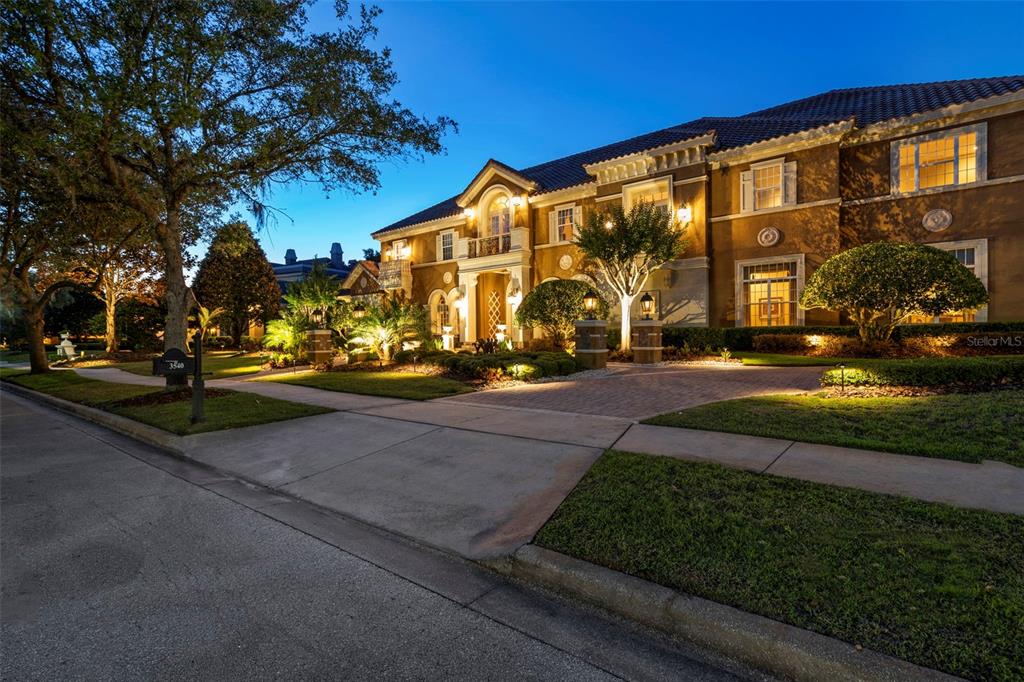 A large, two-story Mediterranean-style house with a brick driveway is illuminated at dusk — 3540 LEGACY HILLS COURT, LONGWOOD, FL