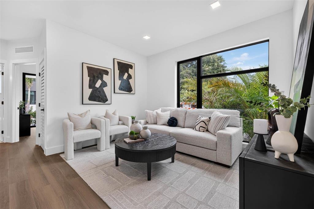 A modern living room features a gray sofa, two armchairs, a round coffee table, and windows — 108 36TH STREET N, ST PETERSBURG, FL