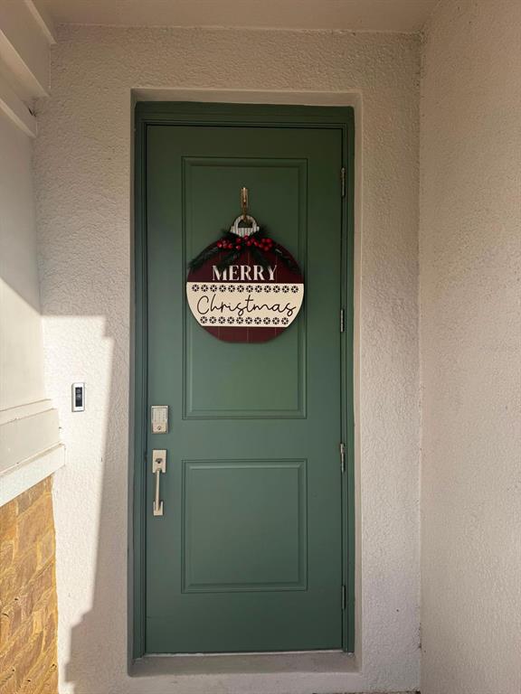 A green front door with a Merry Christmas ornament sign hangs on a white exterior wall — 5779 STEPHENS ROAD, ST CLOUD, FL
