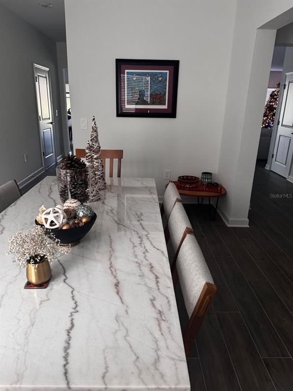 A dining room features a marble-topped table, upholstered chairs, and holiday decor — 5779 STEPHENS ROAD, ST CLOUD, FL