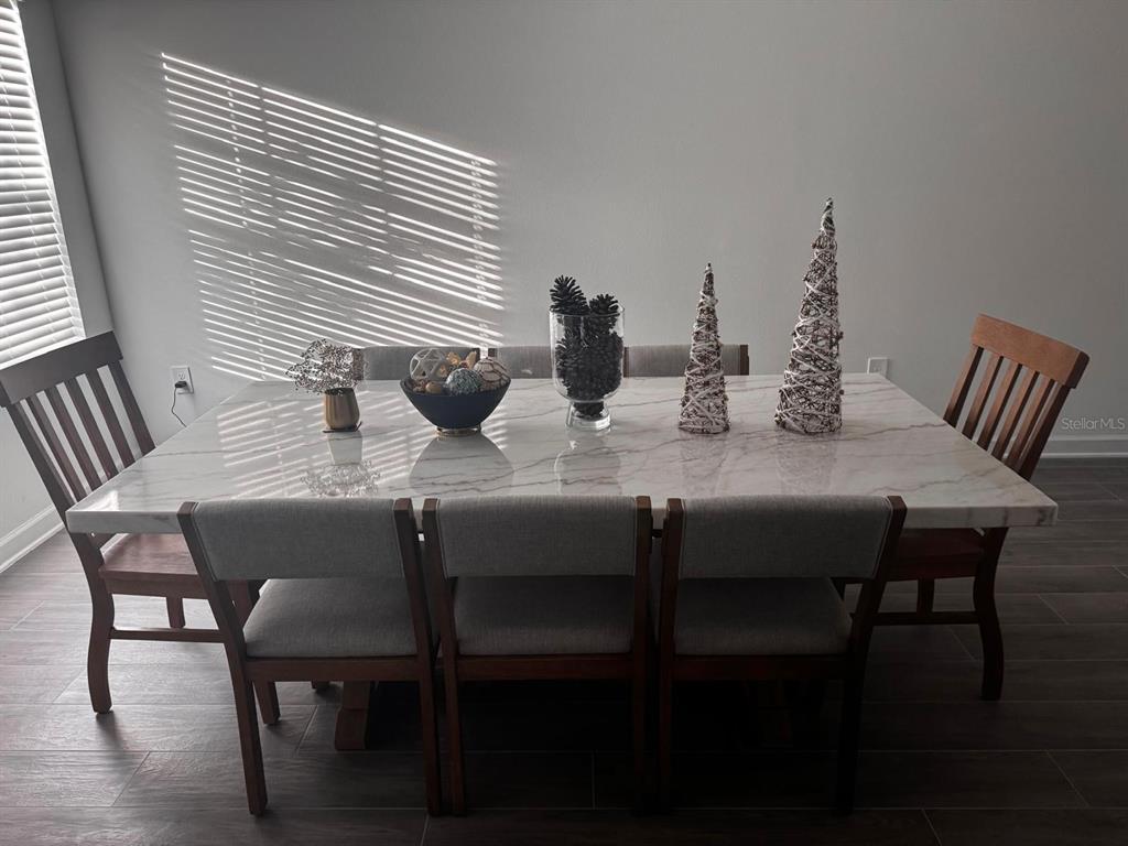A dining room features a marble-topped table with six chairs and decorative centerpieces — 5779 STEPHENS ROAD, ST CLOUD, FL