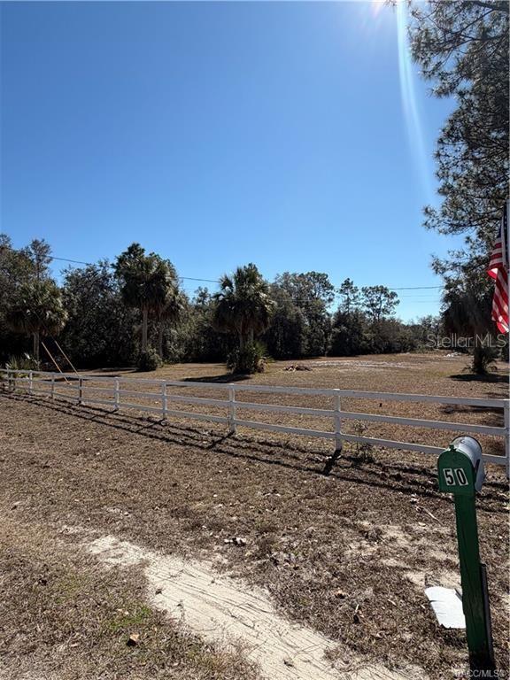 A green mailbox stands in front of a fenced, grassy lot with scattered trees — 10450 SW 60TH STREET, CEDAR KEY, FL
