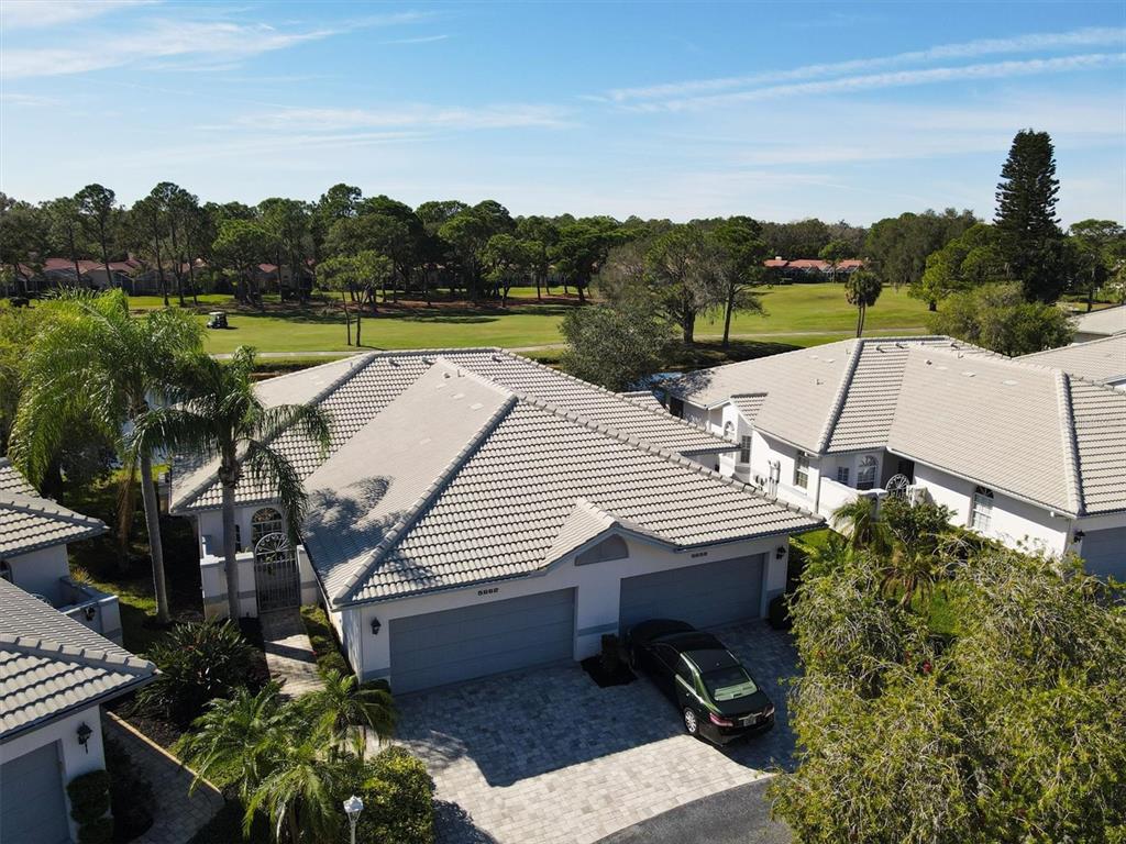 An aerial view shows a residential villa with a tiled roof, garage, and golf course view — 5662 LONG COMMON CIRCLE UNIT 8, SARASOTA, FL
