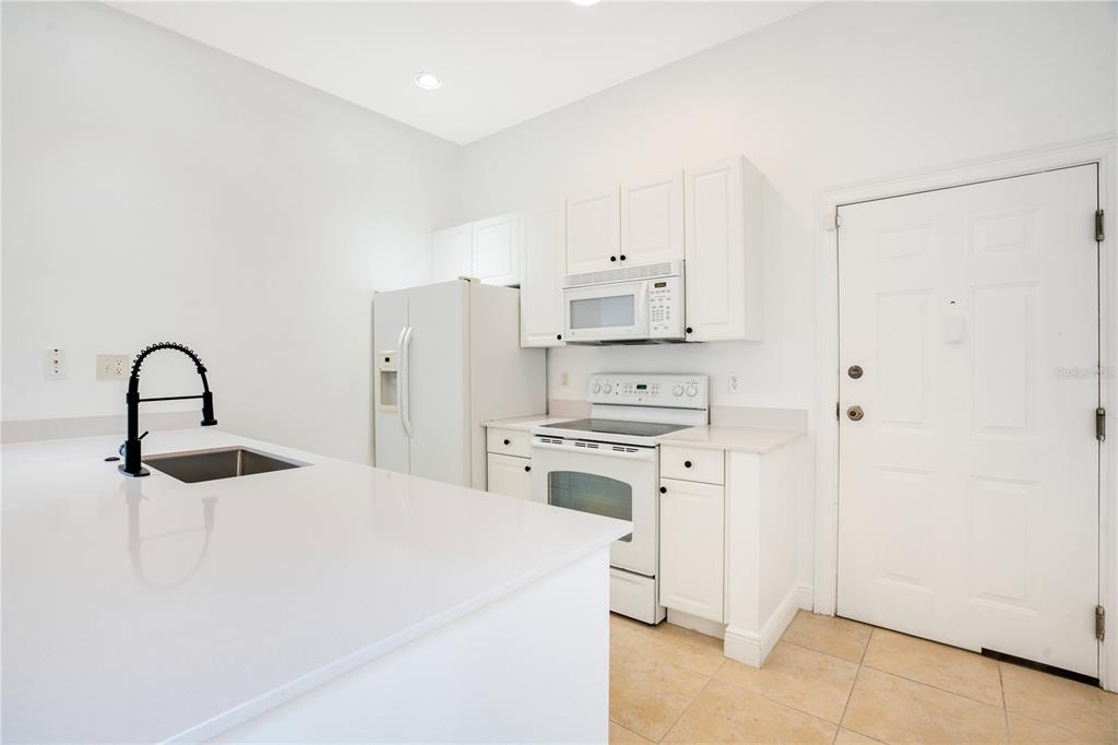 A kitchen features white cabinets, white appliances, a quartz countertop, and a black faucet — 1470 LAKE BALDWIN LANE UNIT C, ORLANDO, FL