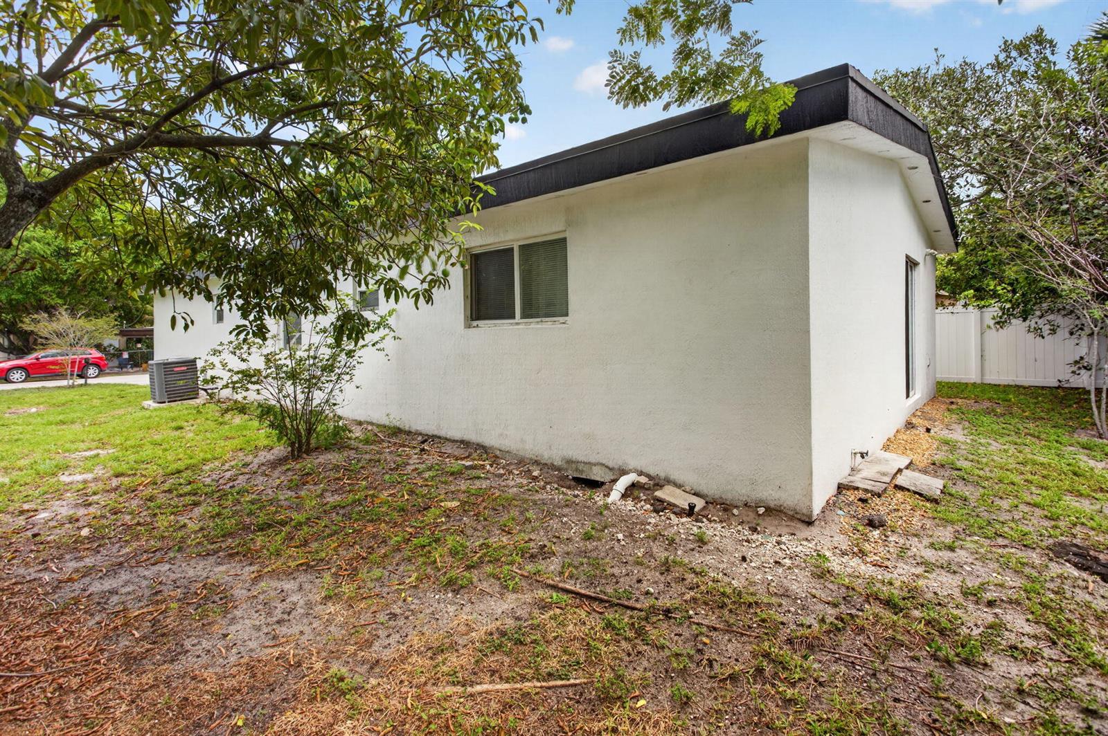 The exterior of a white, single-story house with a flat roof and a small yard — 700 NW 17th Terrace, Pompano Beach FL 33069, POMPANO BEACH, FL