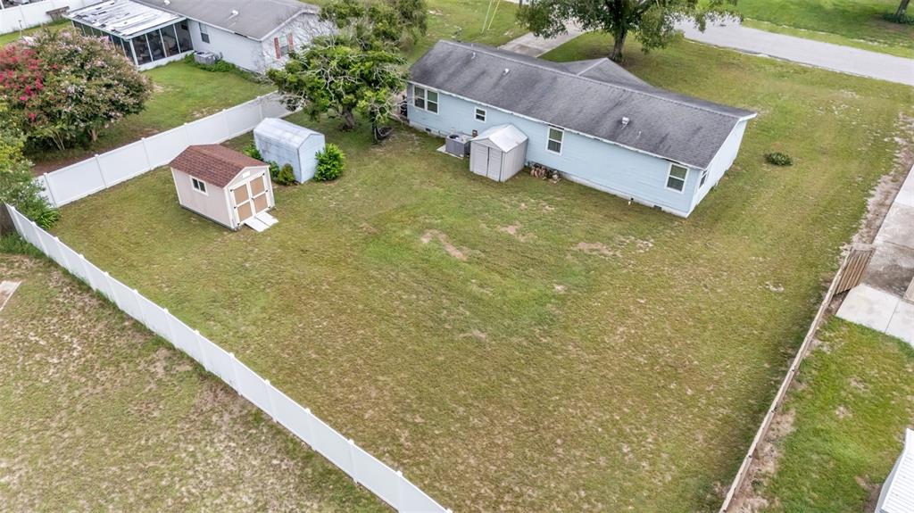 An aerial view shows a fenced backyard with two sheds and a light blue house — 4416 MEADOW RIDGE AVENUE, MULBERRY, FL