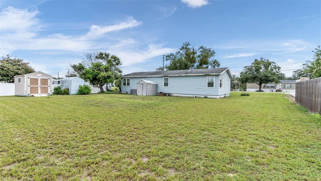 A light blue mobile home sits on a large grassy lot with two storage sheds — 4416 MEADOW RIDGE AVENUE, MULBERRY, FL