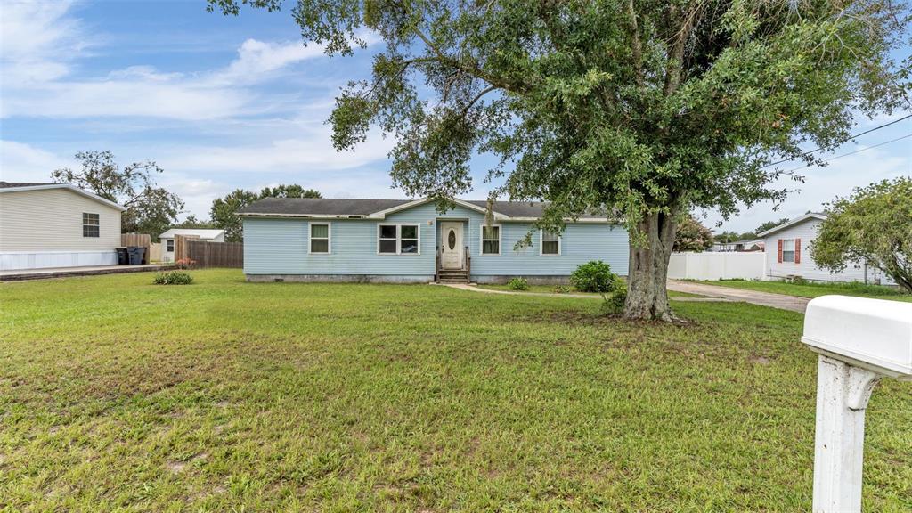 A light blue single-story house with a large tree in the front yard — 4416 MEADOW RIDGE AVENUE, MULBERRY, FL